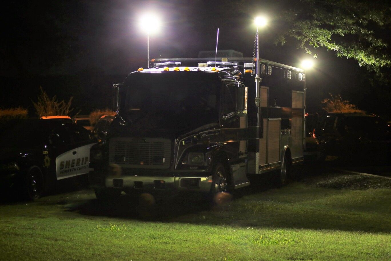 Fire truck parked on grass at night under bright streetlights