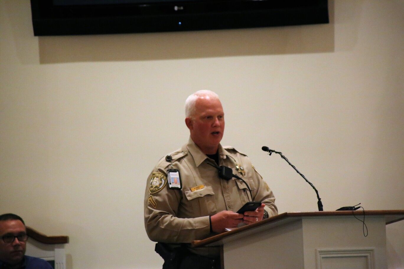 Uniformed officer speaking at a podium in a meeting room