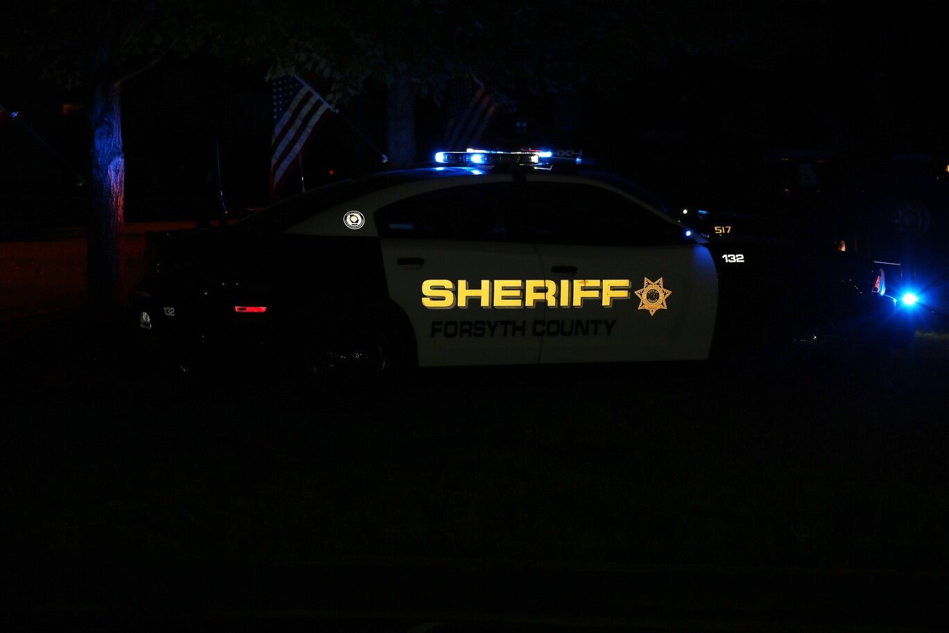 Sheriff patrol car at night with flashing blue lights and “SHERIFF” visible on the door