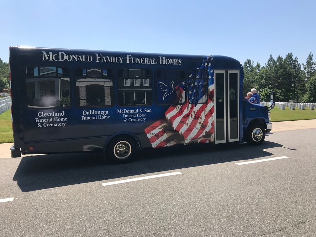 McDonald Family Funeral Home van with patriotic American flag mural parked on a road outdoors