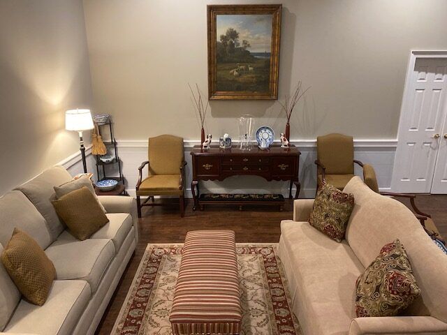 Living room with two sofas, coffee table, lamp, sideboard, and framed painting on the wall