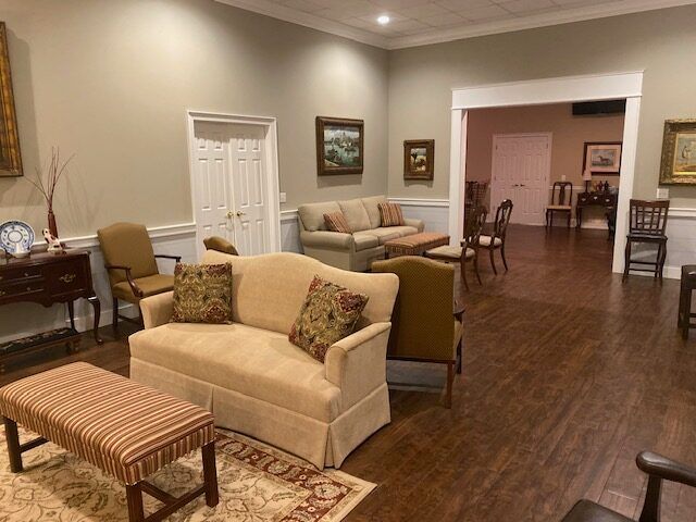 Elegant living room with beige sofas, patterned bench, hardwood floors, and a dining area in the background