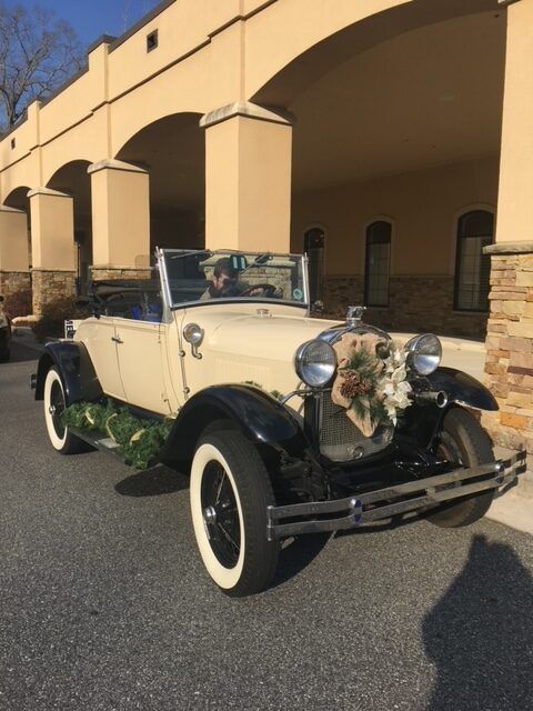 Vintage cream-and-black convertible decorated with flowers, parked under an arched building entrance.