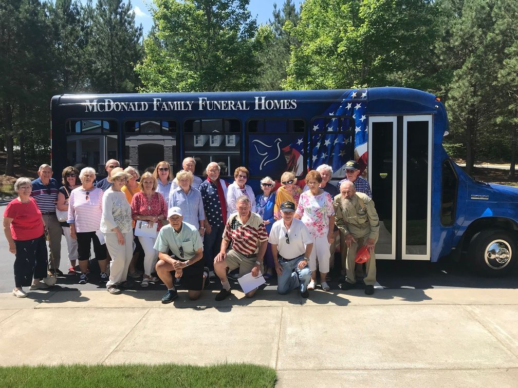 Group posing in front of a blue bus labeled 