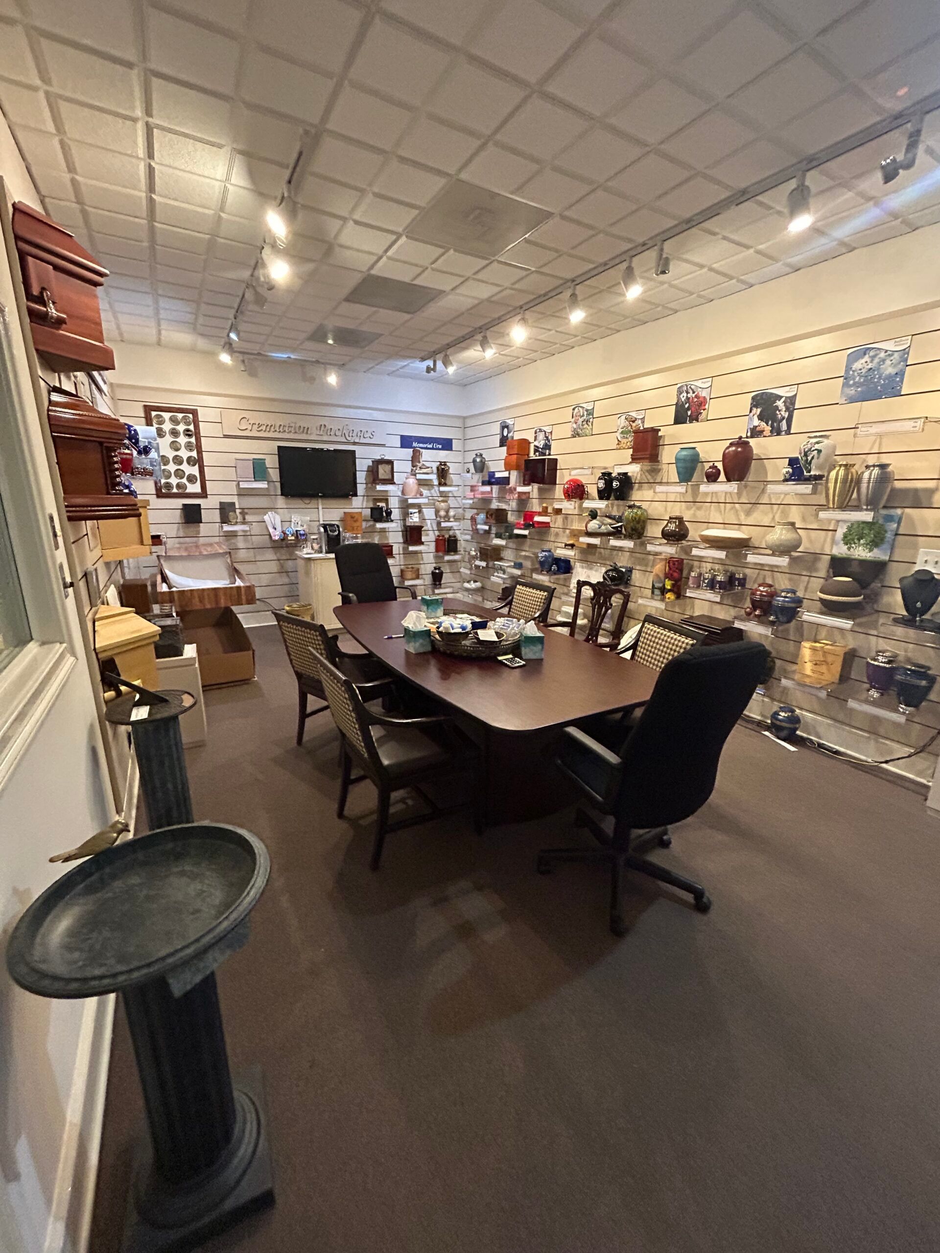 Small retail shop interior with shelves of colorful items, a central table, and a tiled ceiling