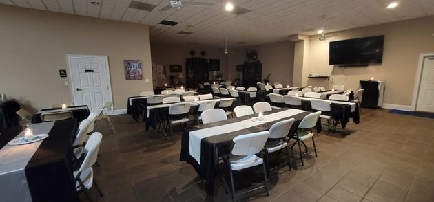 Empty banquet room with long tables and folding chairs under fluorescent lights