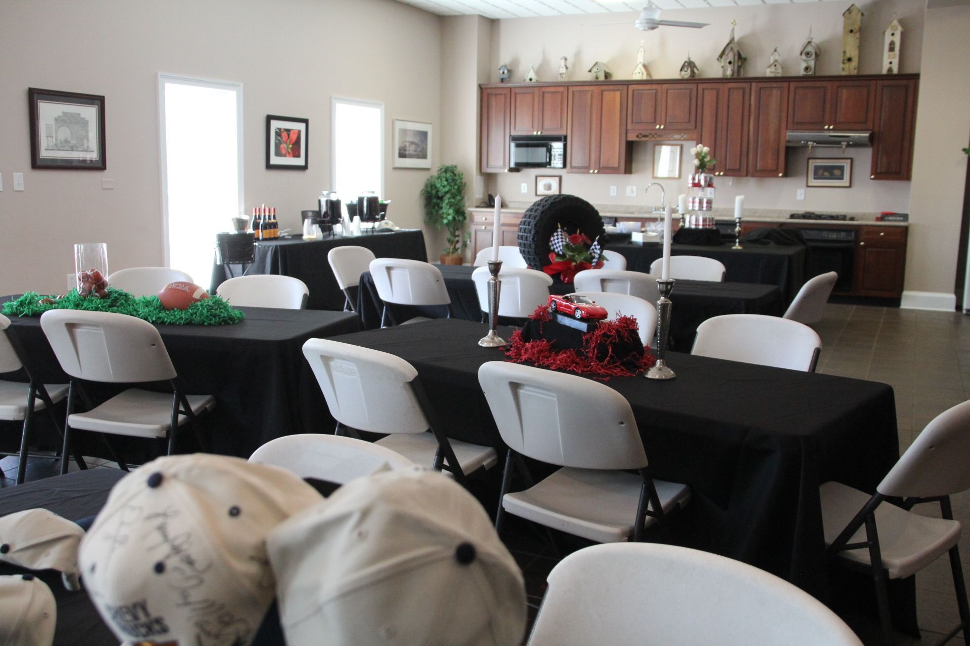 Community hall with tables and chairs set for an event, with a kitchen area in the back.