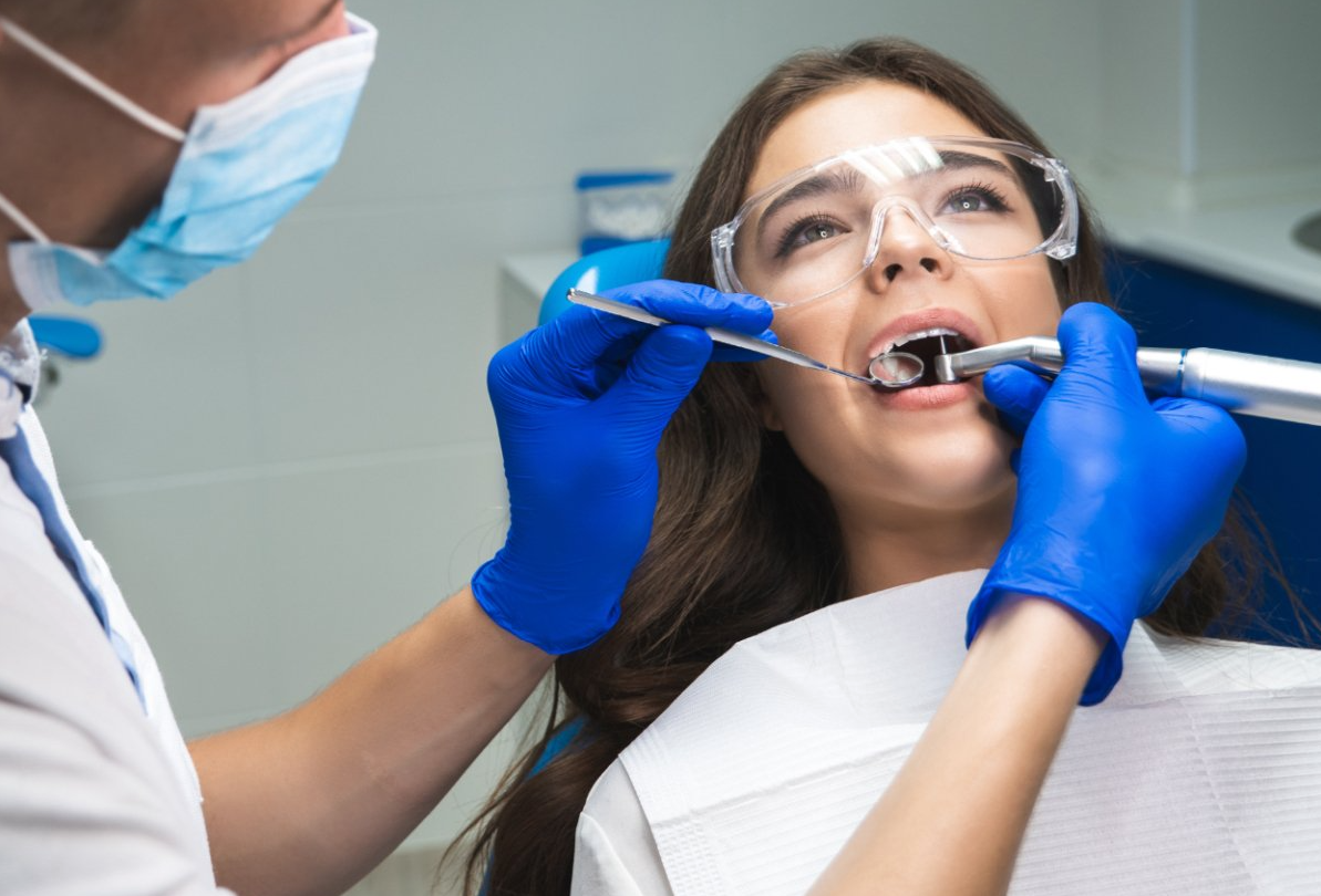 middle age woman looks at new dentures in hand mirror