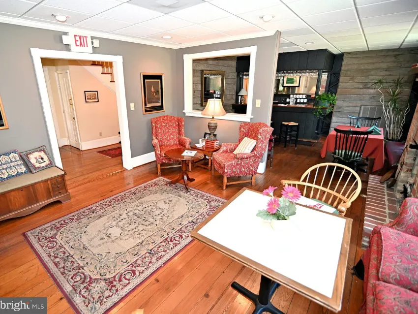 Cozy interior with seating areas, wooden floors, and a view into another room.