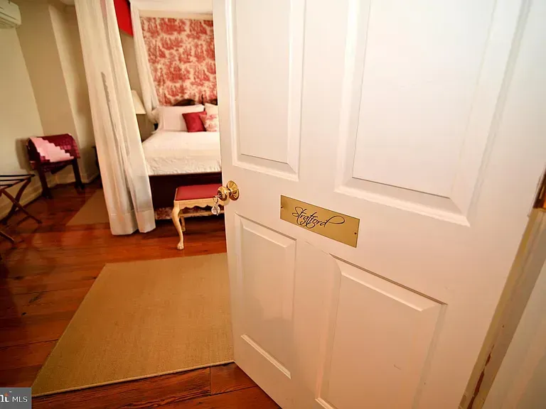 Doorway to a bedroom with a bed and seating. The door has a nameplate.