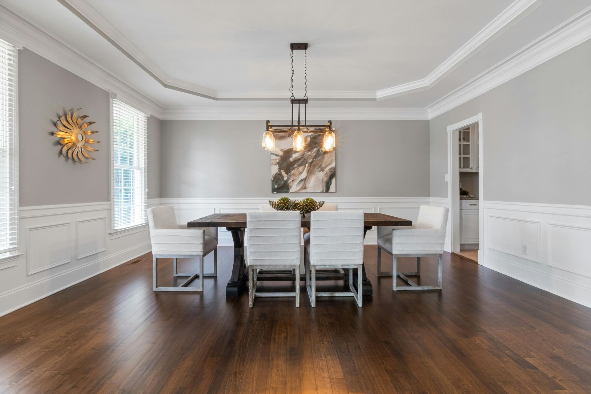 Modern dining room with white chairs, dark wood table, and pendant light over hardwood floors