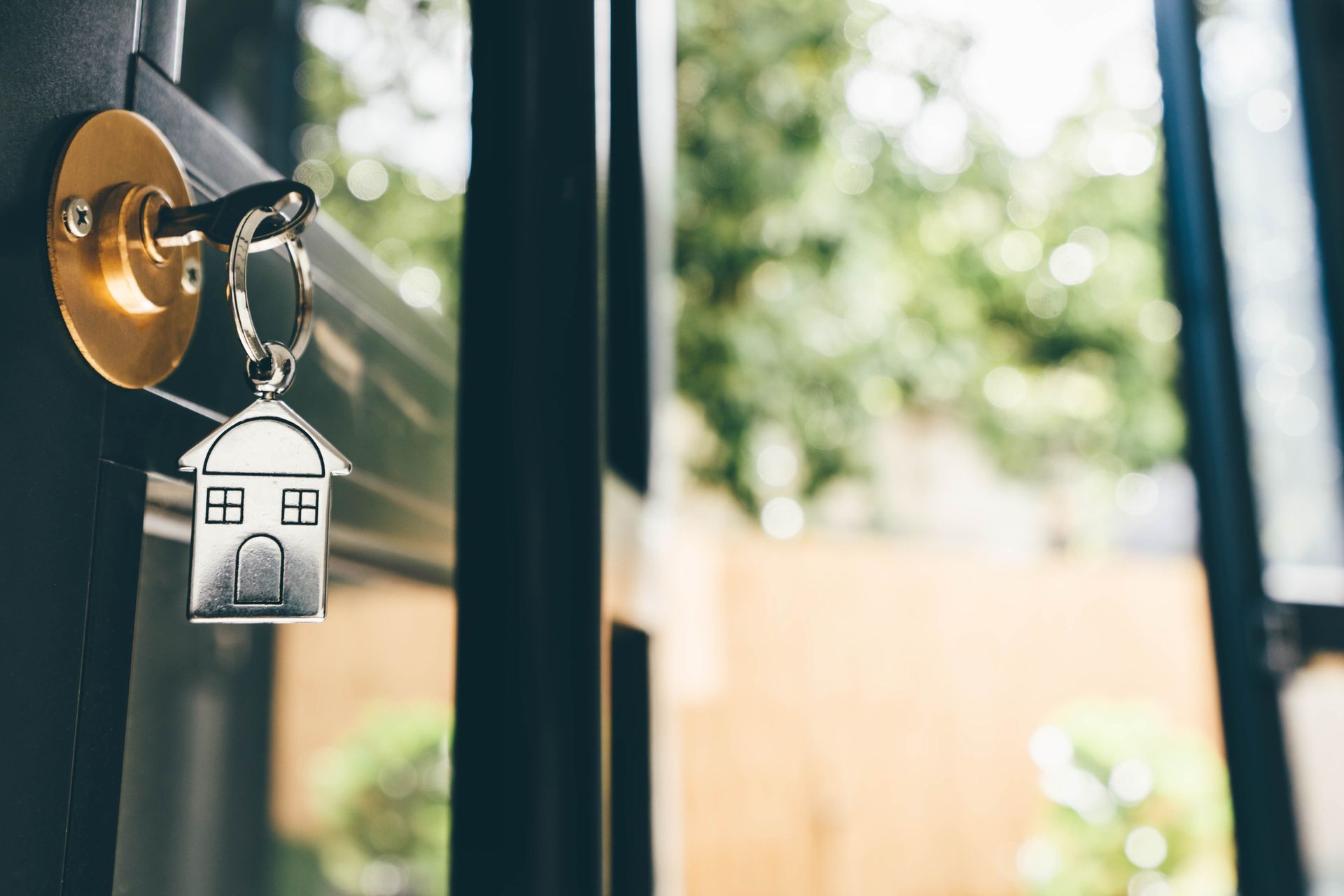 A key with a house keychain hanging on a door.