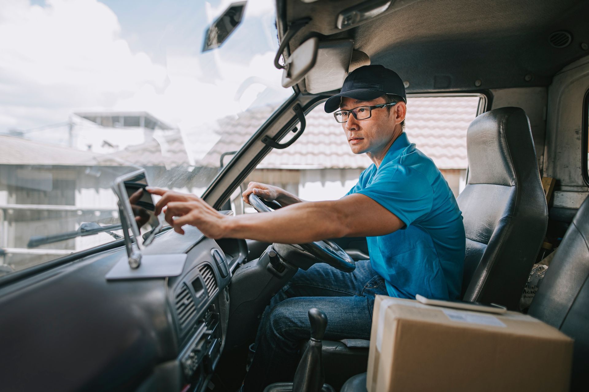A delivery man is sitting in the driver 's seat of a truck. A delivery man is sitting in the driver 's seat of a truck.