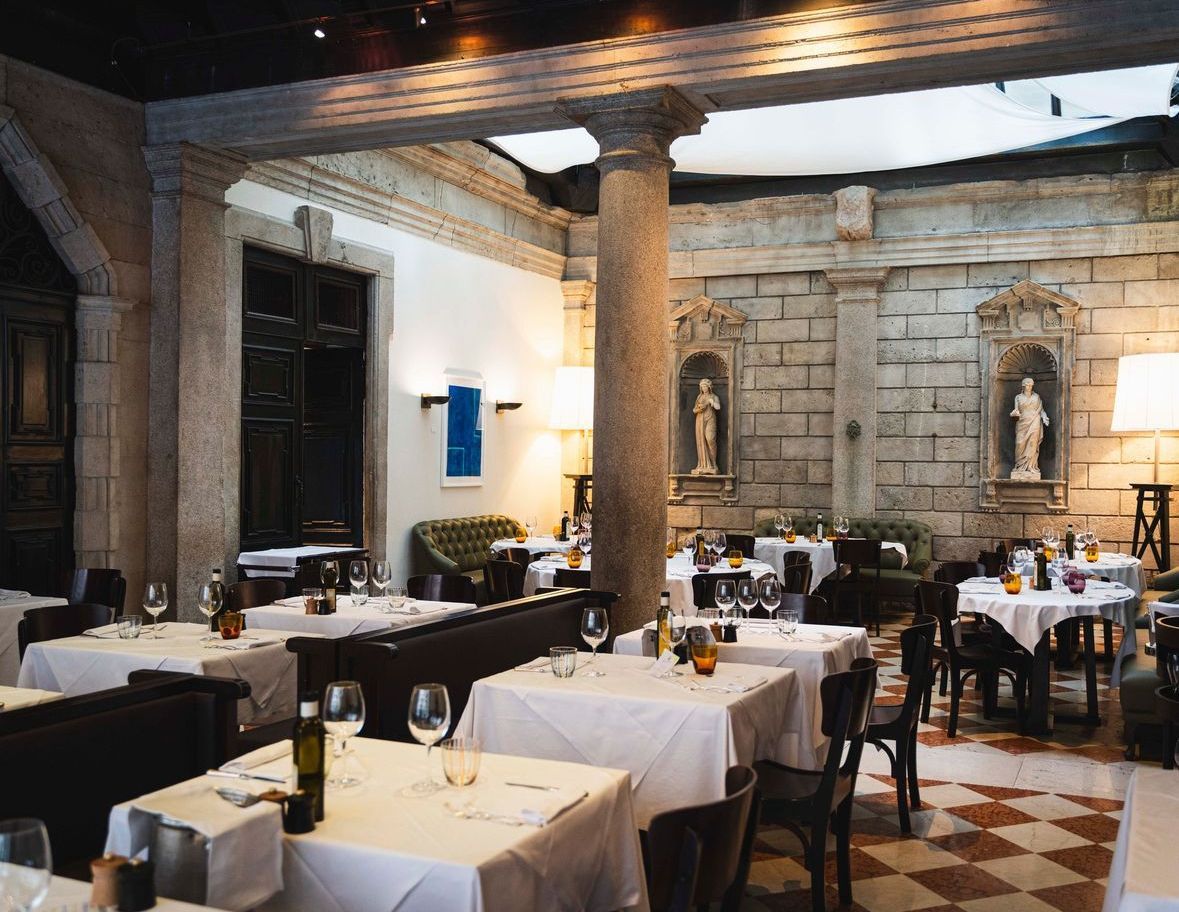 Un ristorante pieno di tavoli e sedie e una statua sul muro.