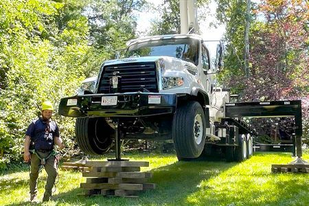 a man is standing next to a large truck that is on a lift .