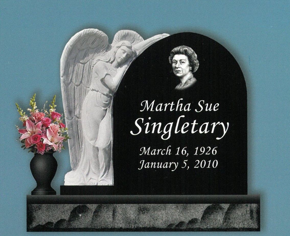 Black granite memorial headstone with angel carving, pink flowers, and inscription for Martha Sue Singletary.