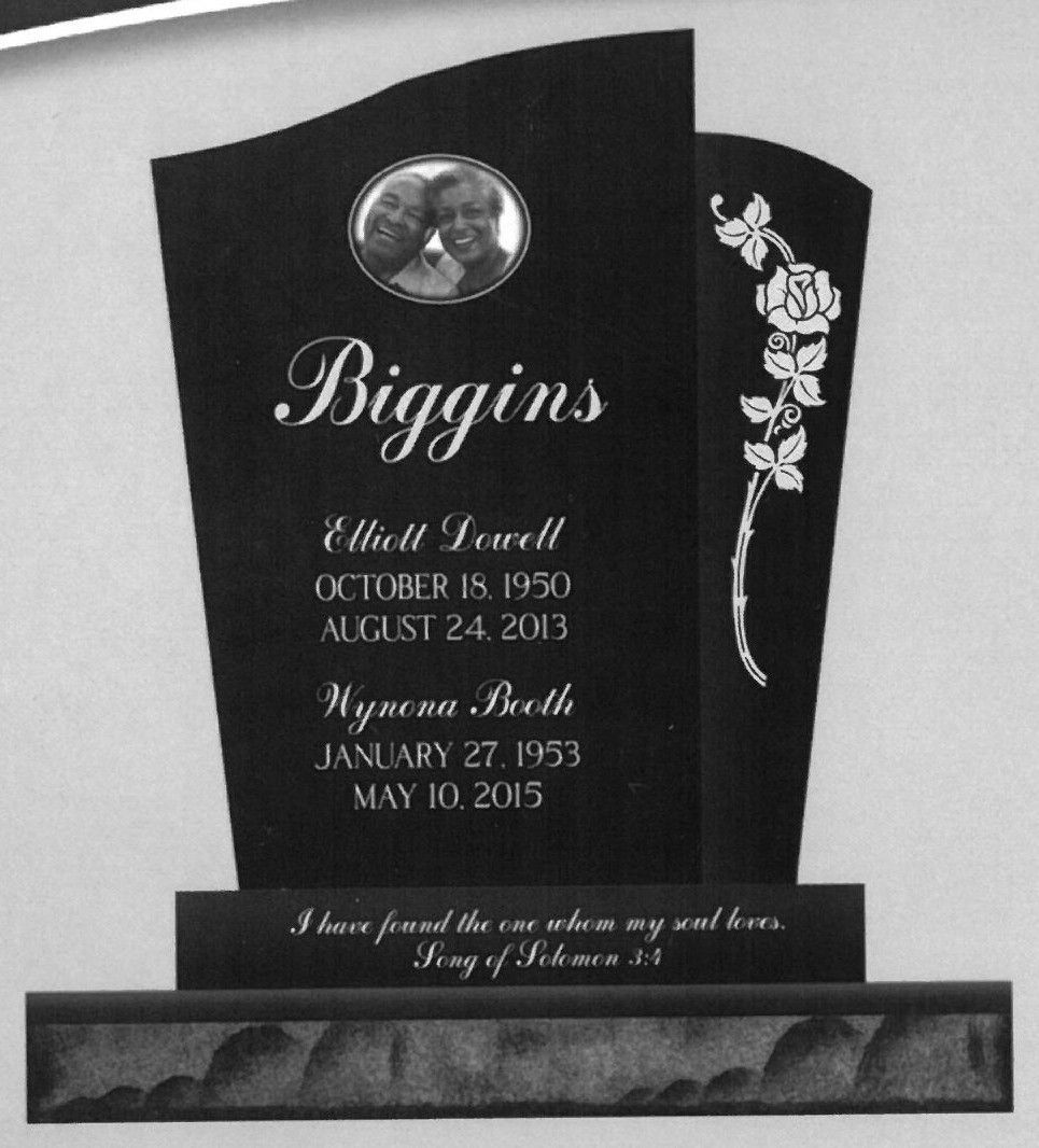 Black headstone memorial with oval photo, white floral engraving, and engraved names and dates.