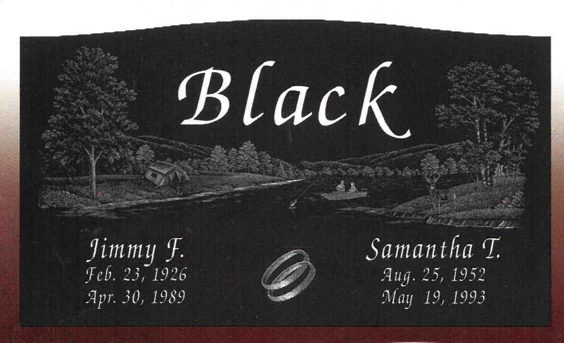 Black memorial headstone with engraved trees, landscape, and two names with dates at the bottom