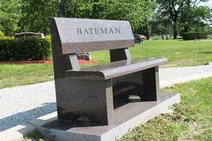 Stone bench memorial with the name “BATEMAN” in a grassy park setting