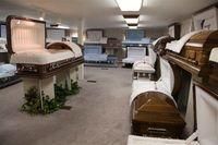 Interior of a funeral home showroom with multiple open and closed caskets displayed in rows