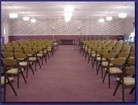 Empty conference room with rows of green chairs and purple carpet facing a front wall