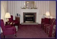 Living room with fireplace, burgundy sofas, lamps, and purple carpet