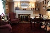 Cozy living room with fireplace, red armchairs, and small dining table under warm wall lights