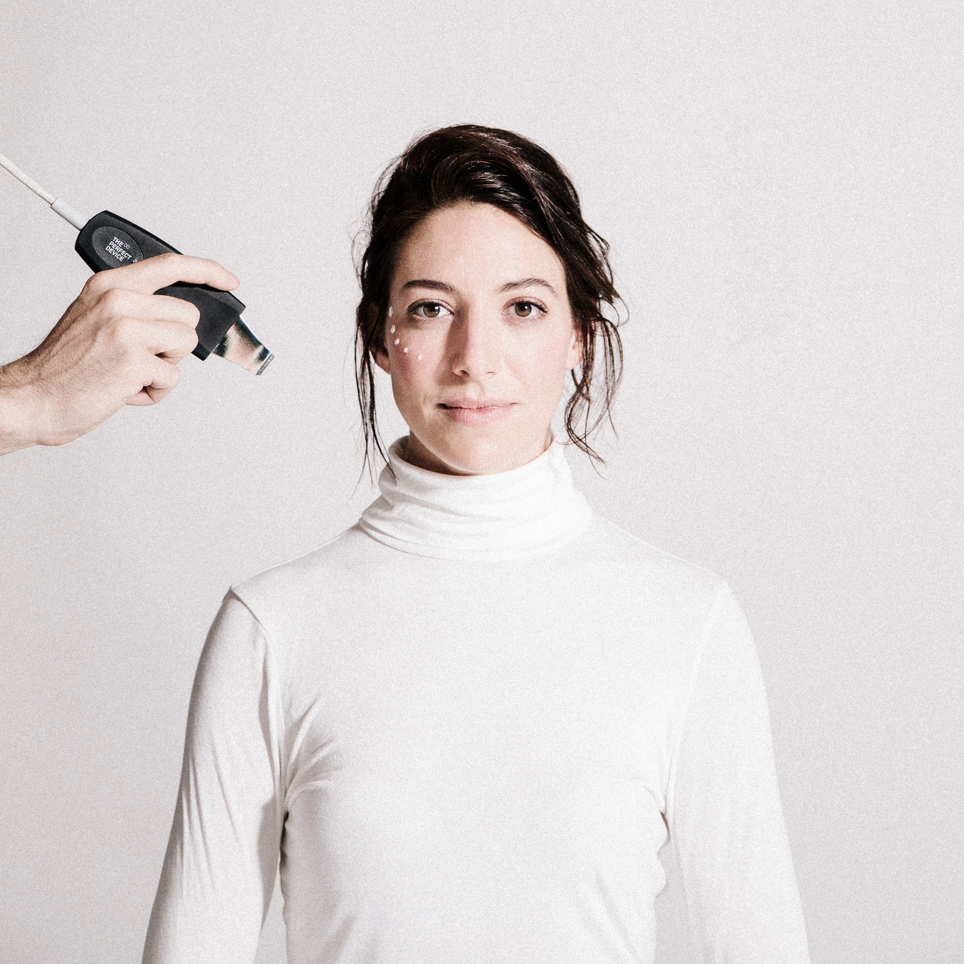Eine Frau in einem weißen Rollkragenpullover wird von einer Person vermessen