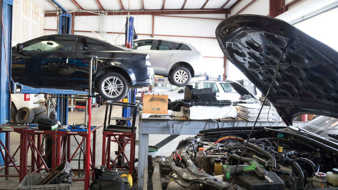 Car repair shop with cars on lifts and open hoods, showing engine work in progress