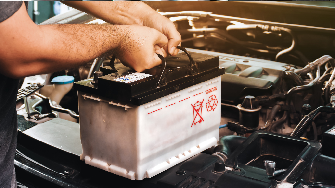 Hands installing a car battery in an engine bay