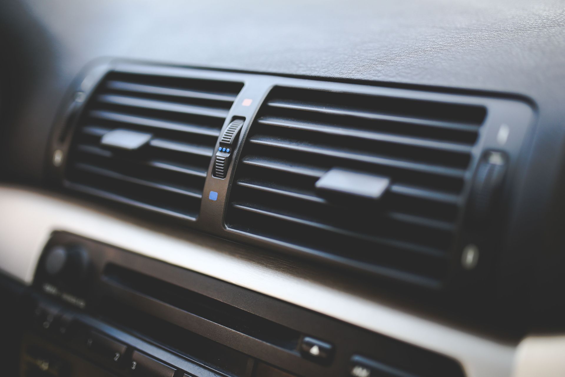 Close-up of a car dashboard air vent with black slats and silver trim