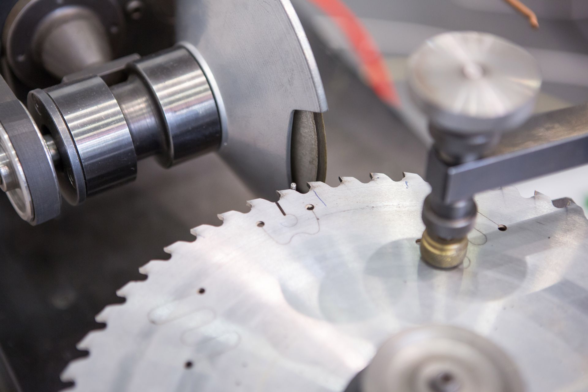 Close-up of a metal circular saw blade being machined by industrial tools in a workshop