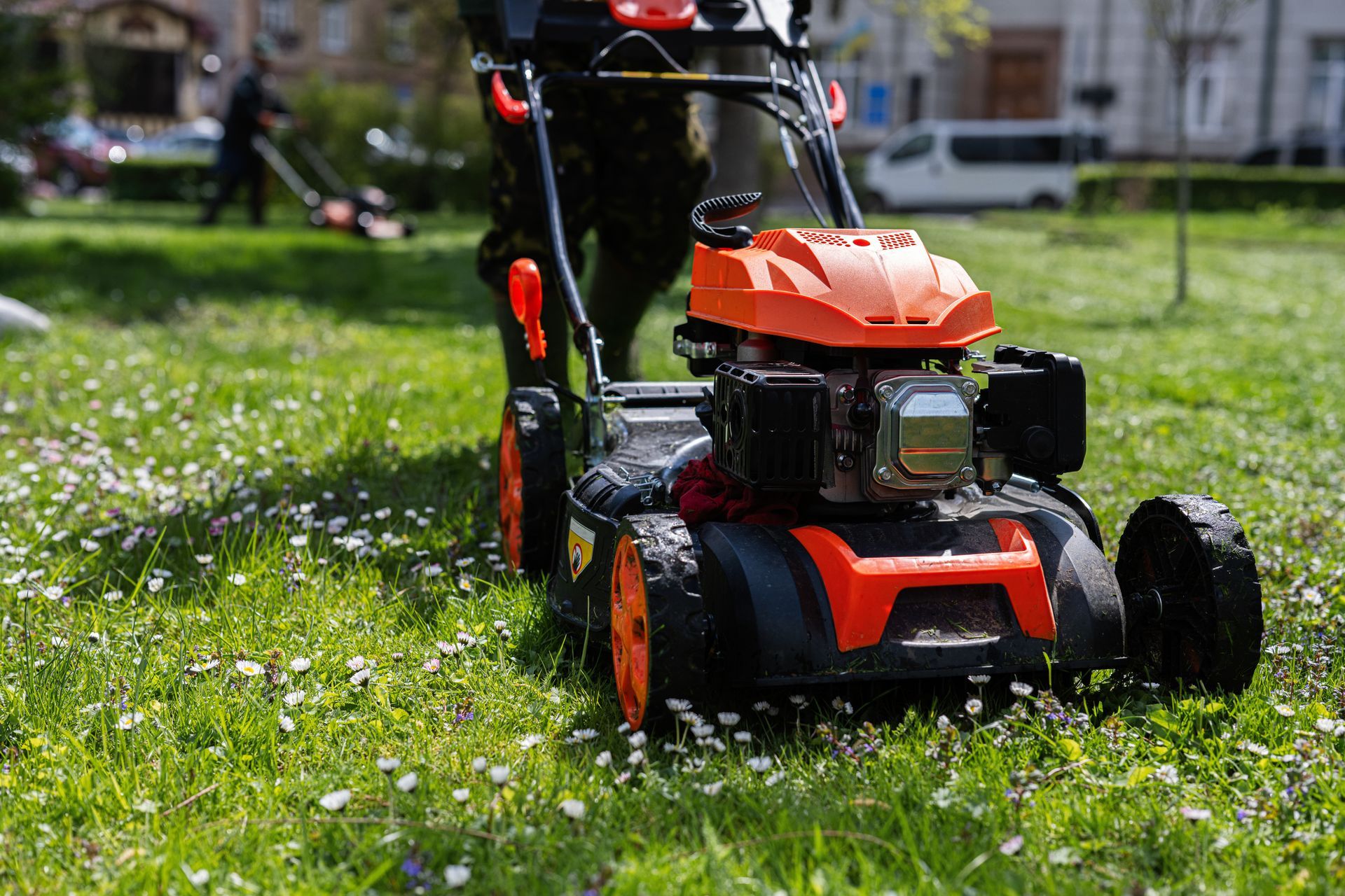 Orange lawn mower cutting grass in a sunny yard