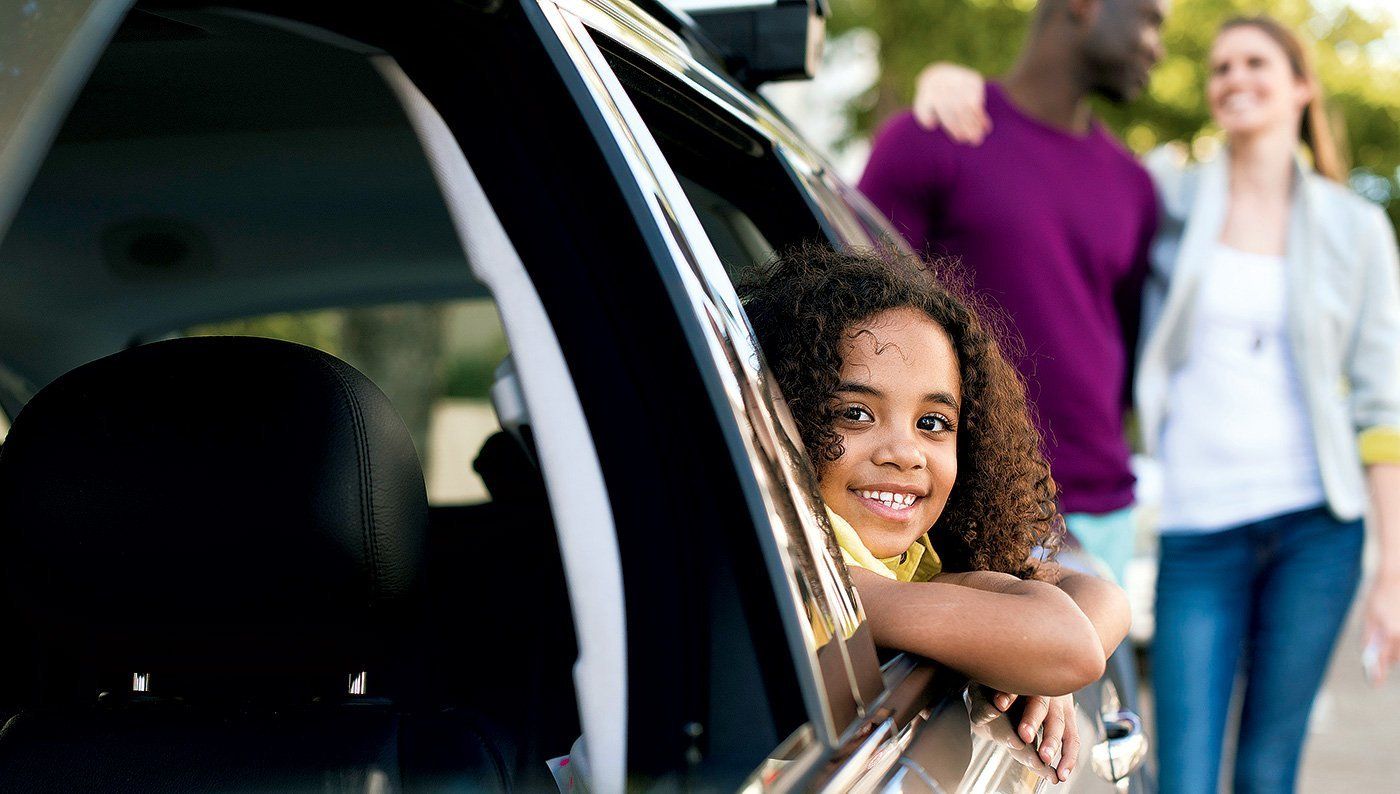 A little girl is looking out of the window of a car.