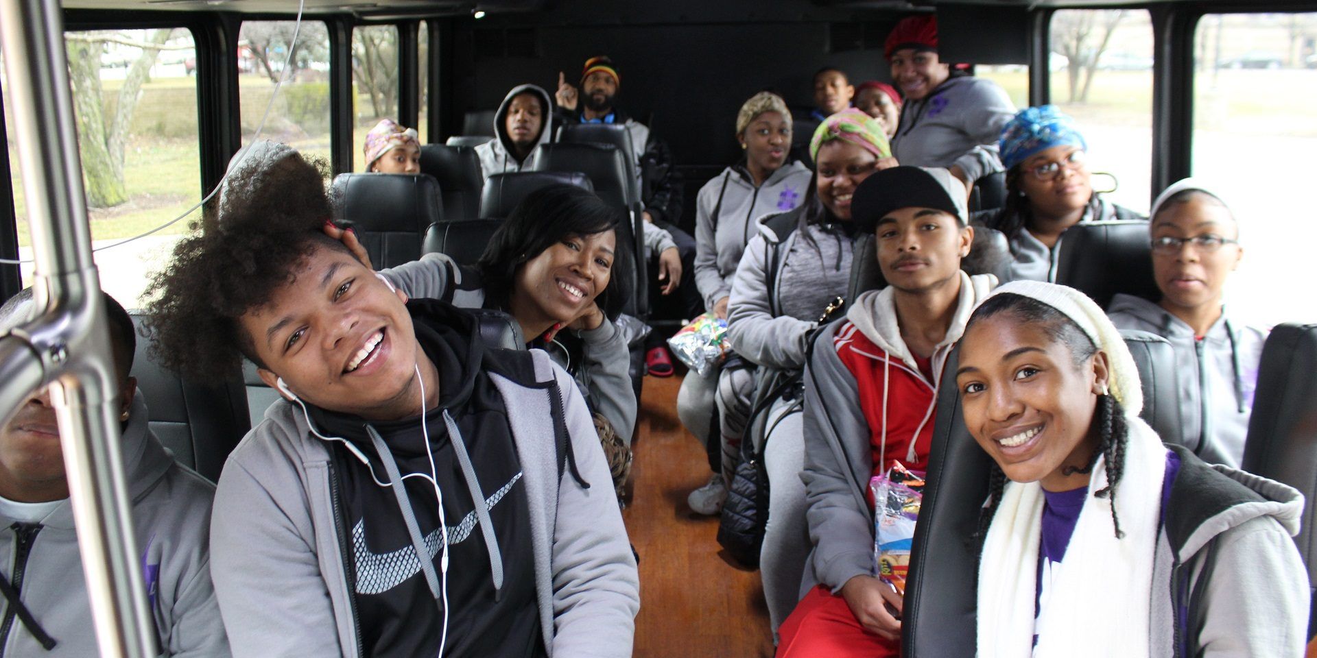 A group of people are sitting on a bus and smiling.