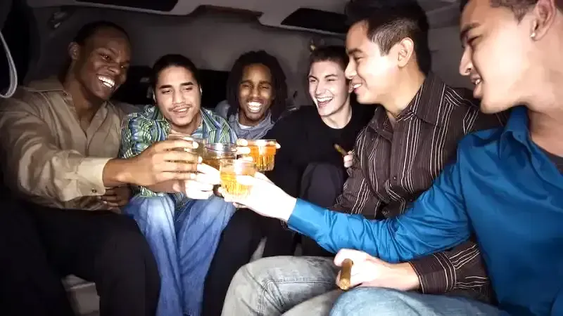 A group of young men are toasting with drinks in a limousine.