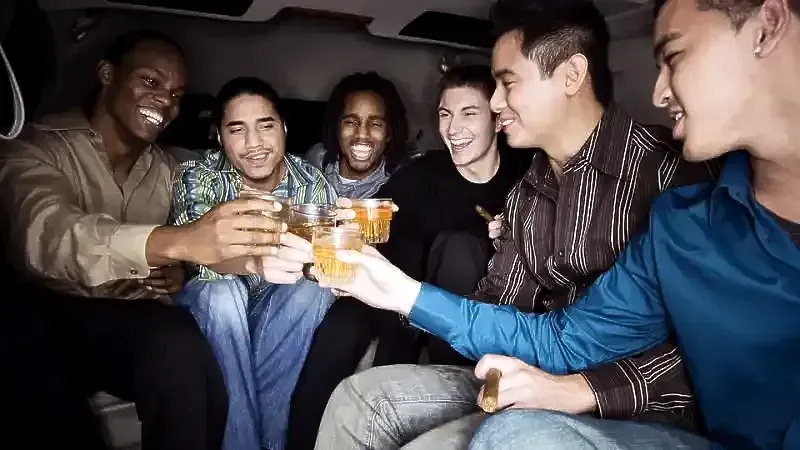 A group of young men are toasting with drinks in a limousine.