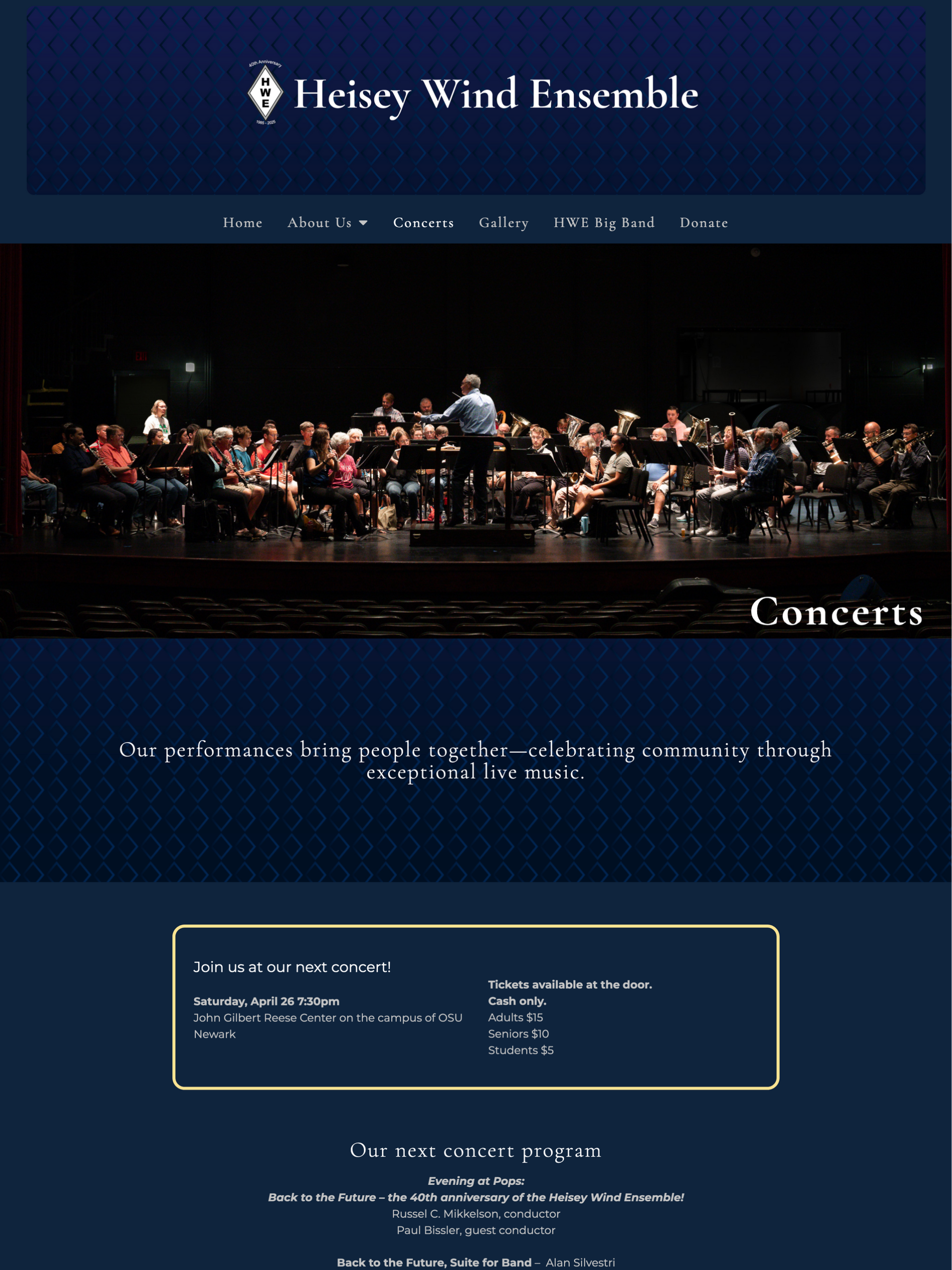 Heisey Wind Ensemble concert. Orchestra on stage under a conductor's direction, dark blue background.