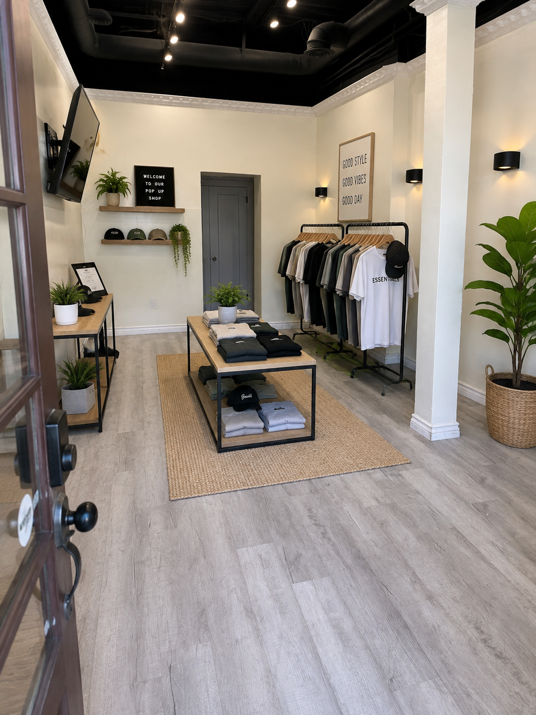 Minimal clothing store interior with folded sweaters on a table and hanging neutral-toned garments on a rack.