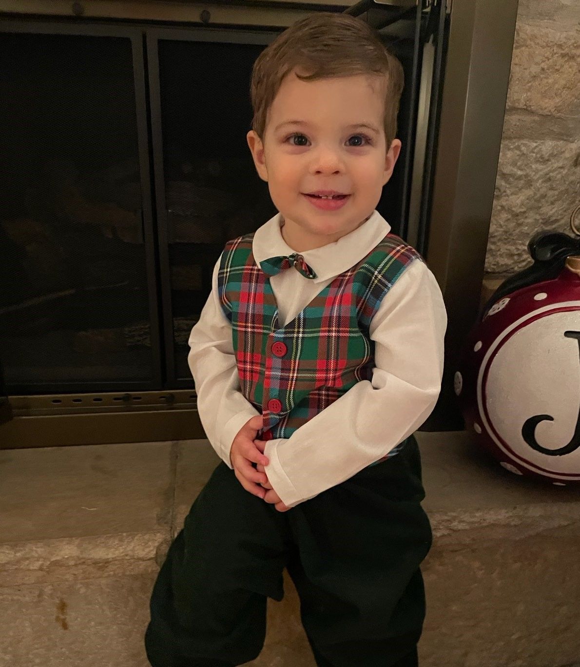 A little boy is wearing a plaid vest and bow tie