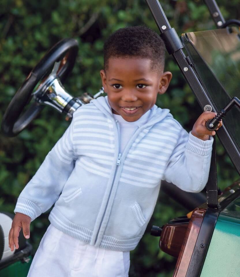 A young boy is standing next to a golf cart