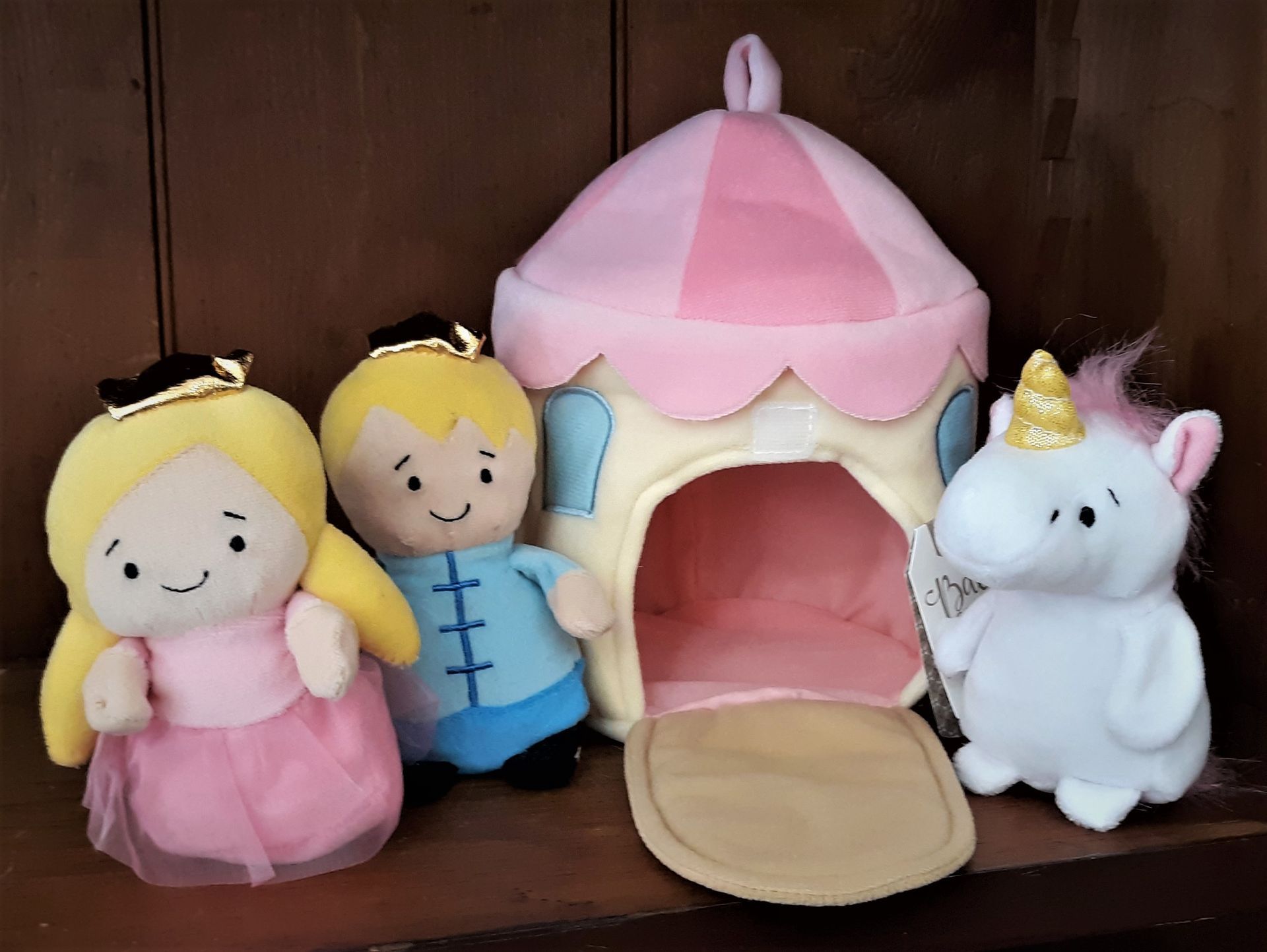 Three stuffed animals are sitting next to each other on a wooden shelf.