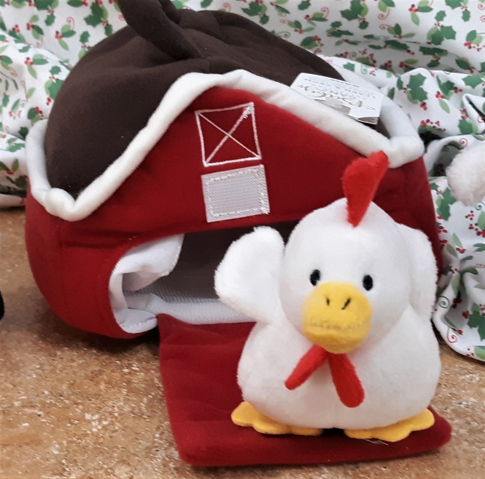 A stuffed chicken sits in front of a red barn