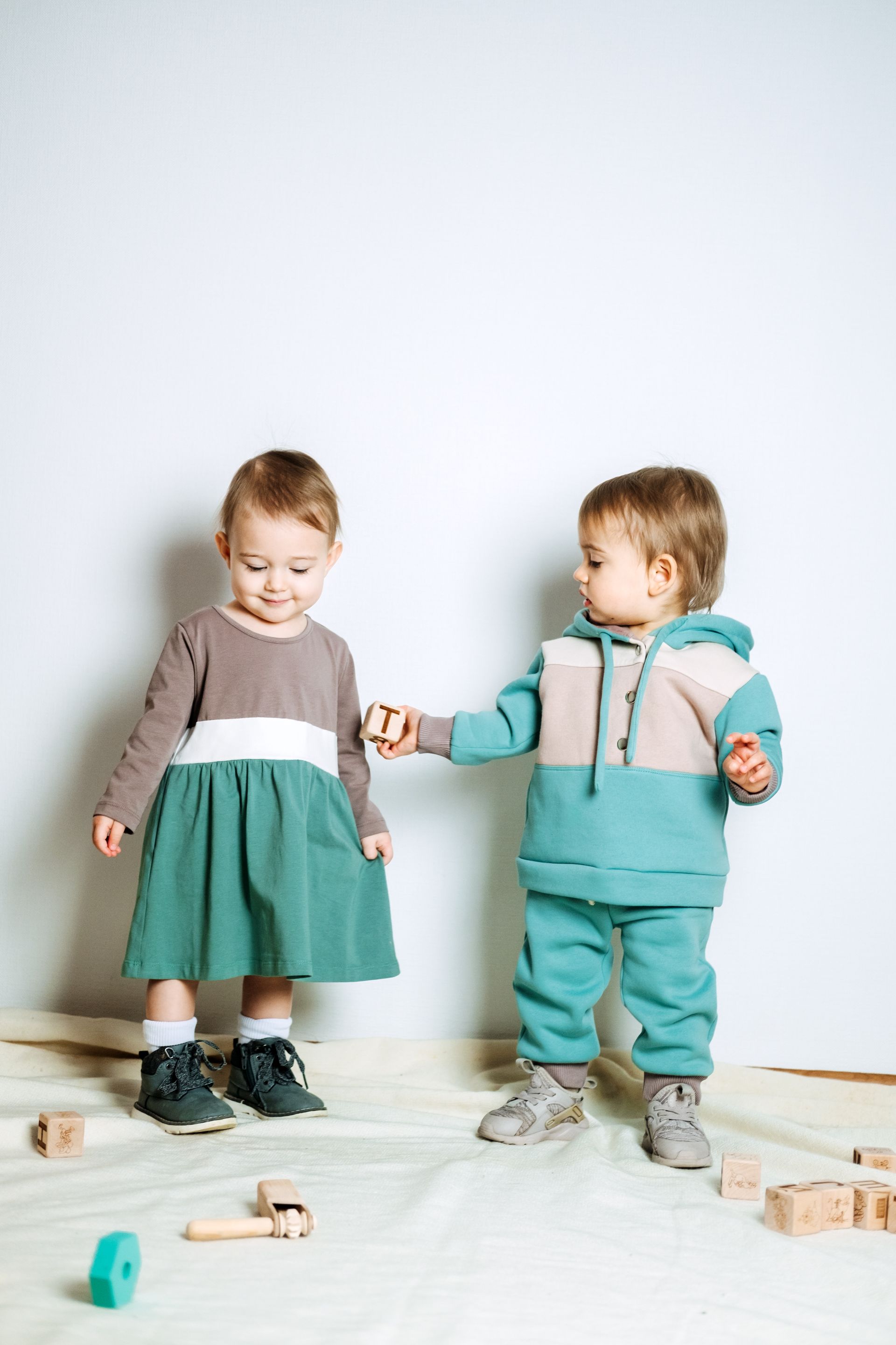 A boy and a girl are standing next to each other holding hands.