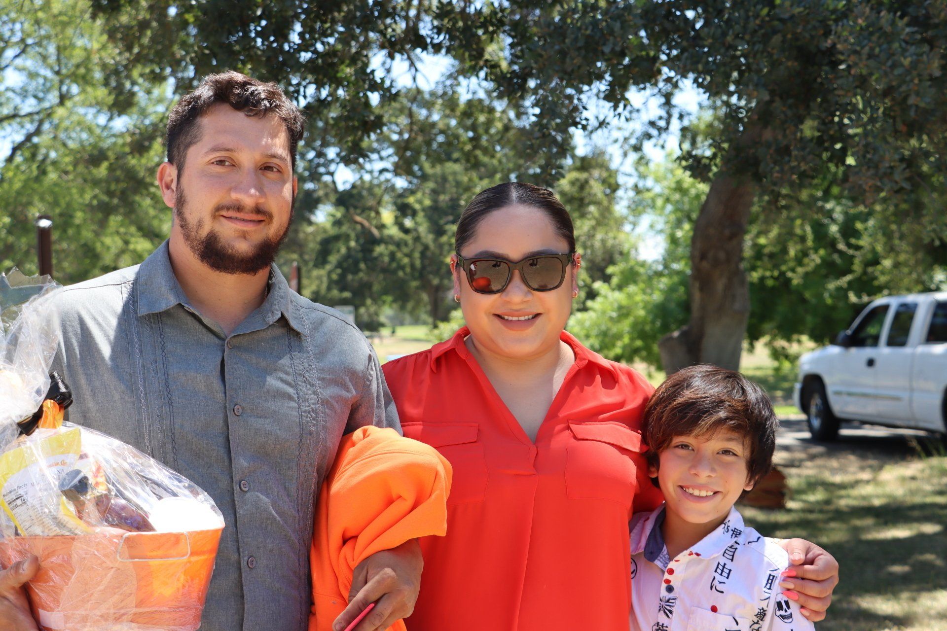 A man , woman and child are posing for a picture in a park.