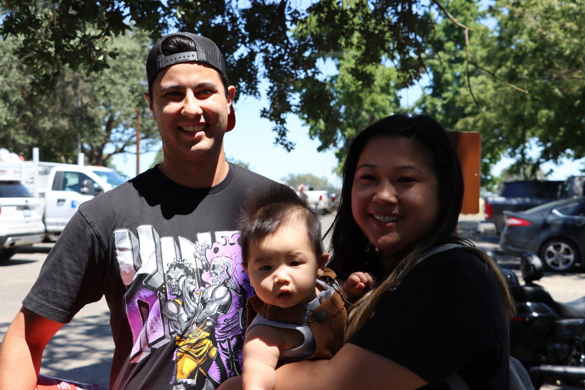 A man and a woman are holding a baby in a parking lot.