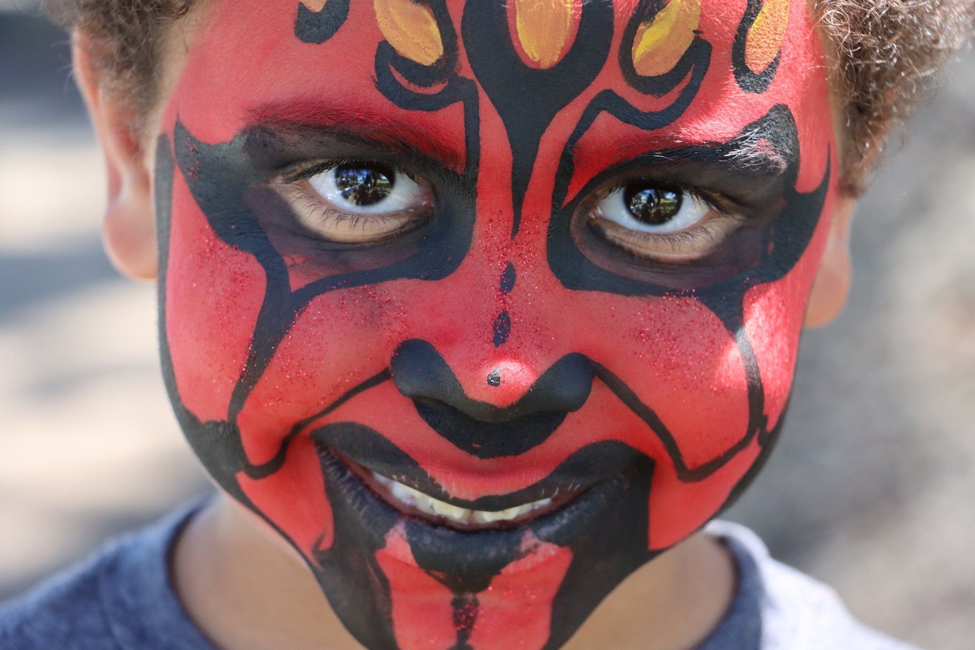 A young boy with his face painted like darth maul