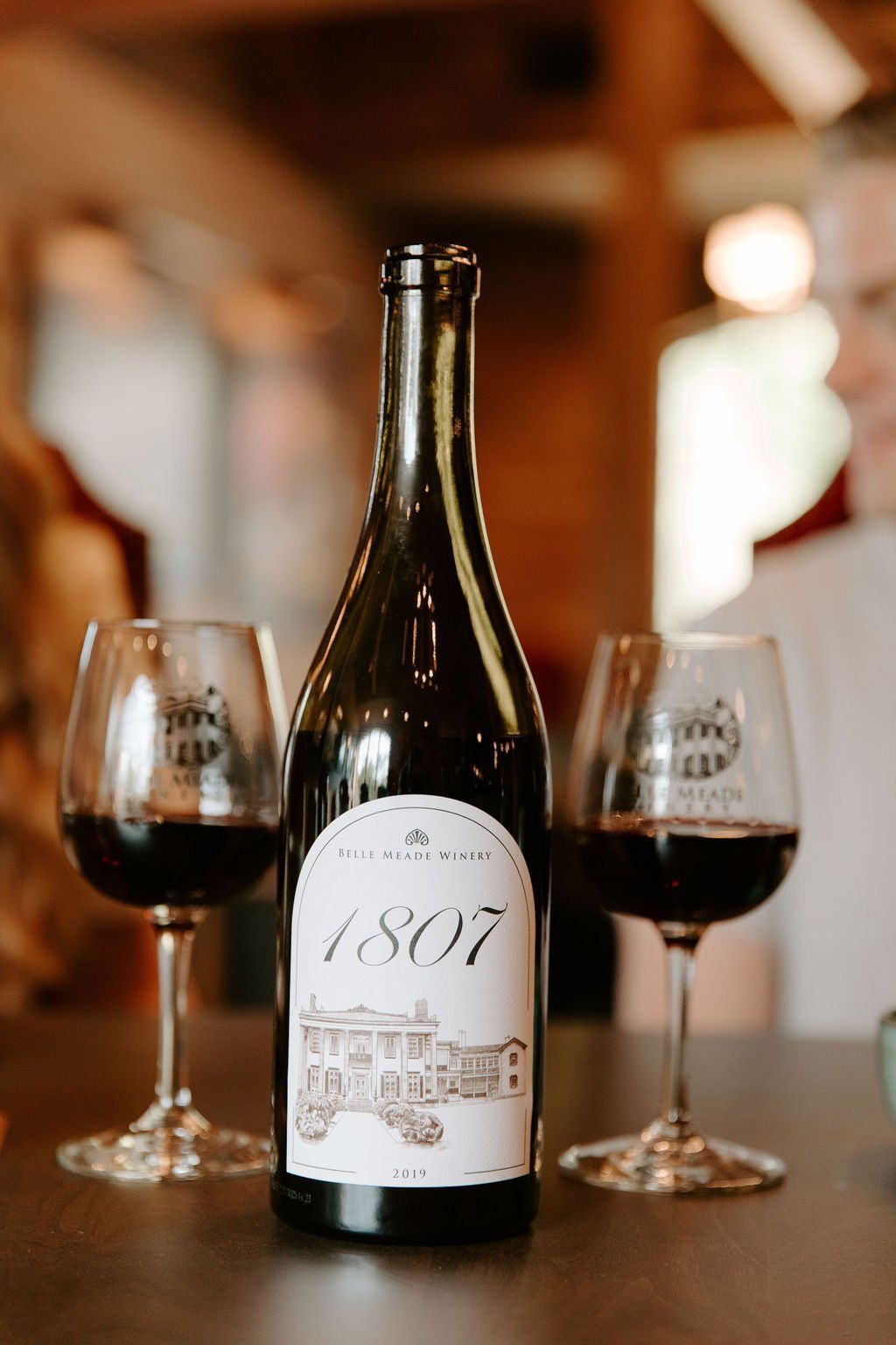 Wine bottle and two glasses with red wine on a table. The label reads