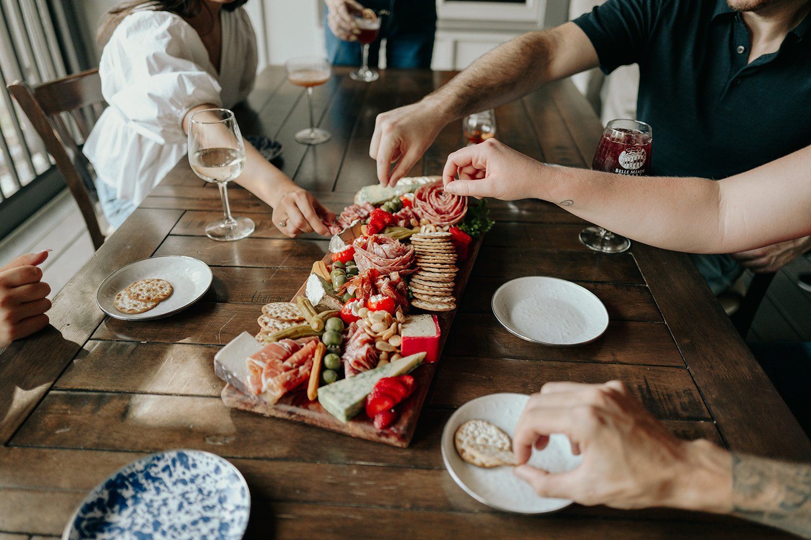 People gathered around a wooden table, enjoying charcuterie.