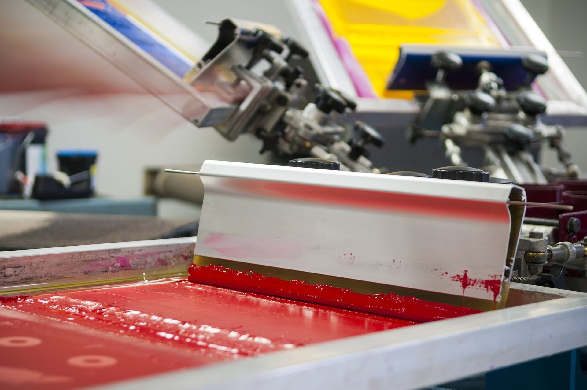 A screen printing machine is printing a piece of paper on a table.